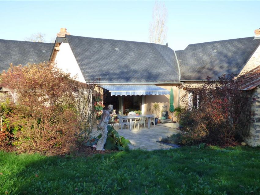 Maison ancienne avec grandes baies vitrées ouvrant sur terrasse.